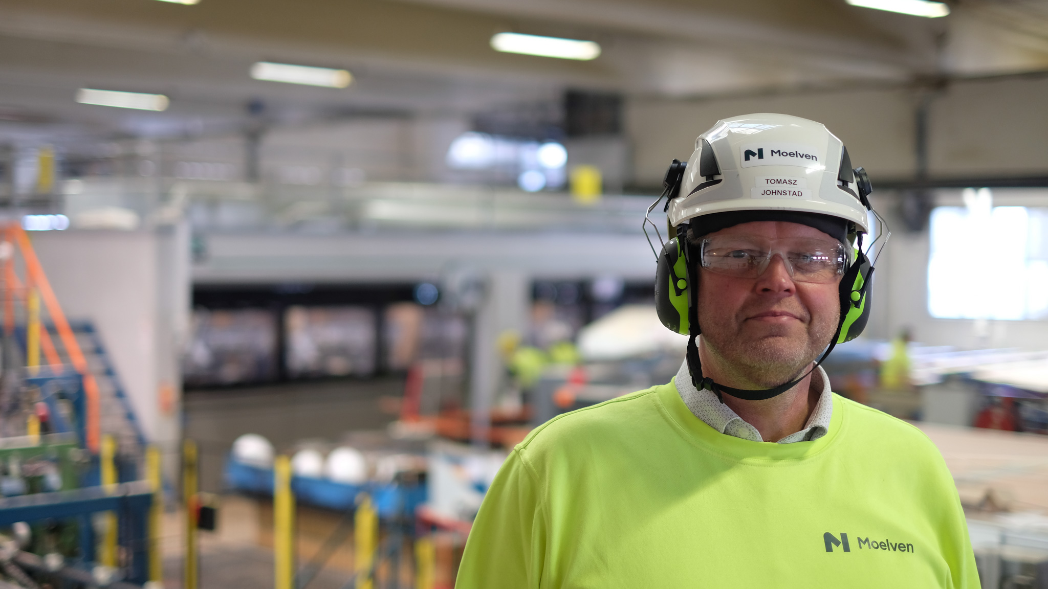 En ansatt i Moelven Langmoen med vernebekledning foran ny høvel. Foto