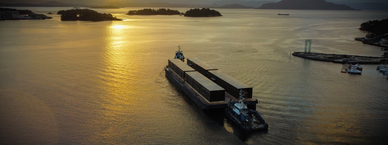 Moelven Byggmodul - moduler på lekter på vei til Odda i solnedgang